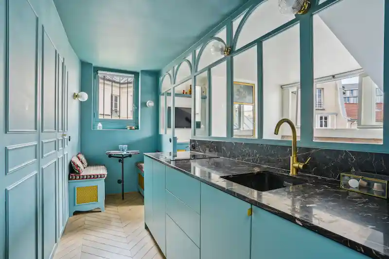 Cuisine design bleue avec plan de travail en marbre noir et verrière
